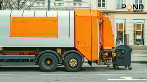 garbage truck collecting waste from a black bin on a city street
