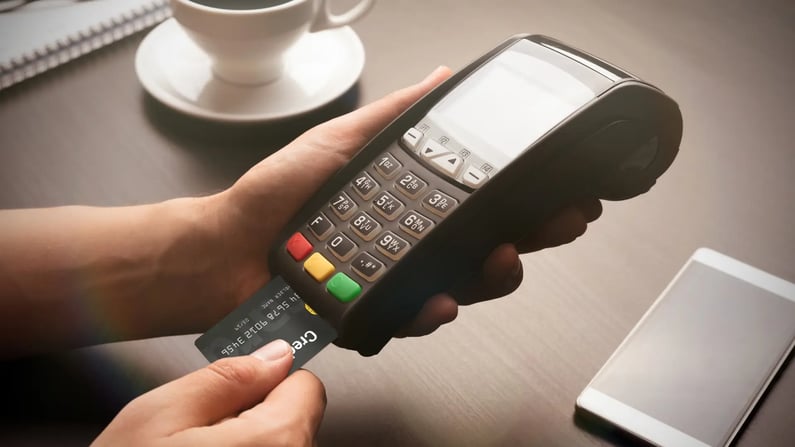 Person inserting a credit card into a payment terminal on a table