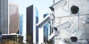 Multiple security cameras mounted on a wall with city buildings in the background