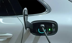 Electric vehicle charging at a station, close-up of charging port.