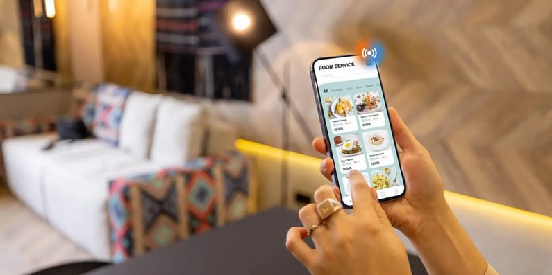 Guest using a smartphone to order room service in a smart hotel.