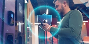 Man using a smartphone at a self-service system with a digital security shield overlay, ensuring secure transactions.