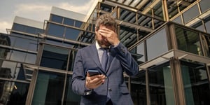 Stressed businessman checking his smartphone outside an office building