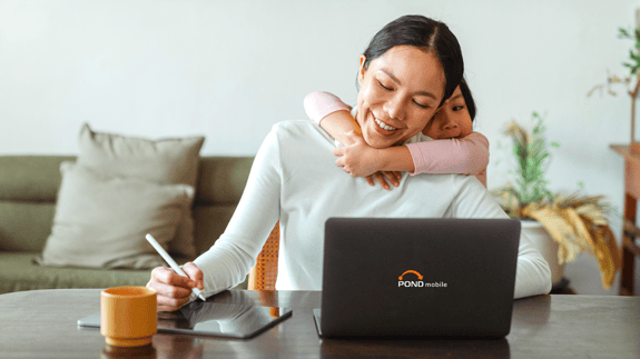 Woman with kids working from home using a tablet and laptop