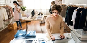 Retail staff using laptop with customers in store