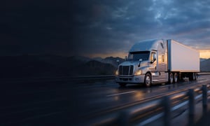 Connected freight truck traveling on a highway at dusk