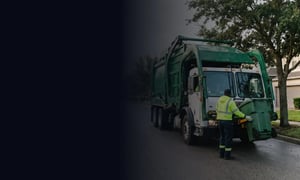 Waste collection worker beside a connected garbage truck on a residential route.